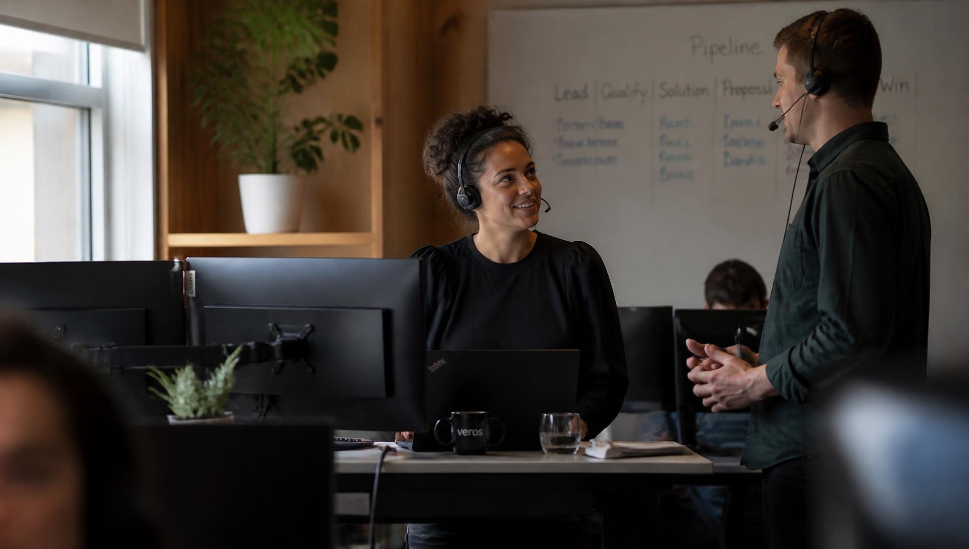 Sales team on calls in a modern office with a pipeline drawn on a whiteboard behind them